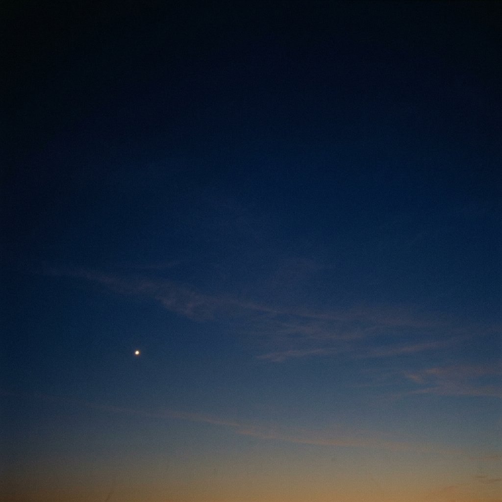Deep indigo twilight sky, single planet visible near the horizon